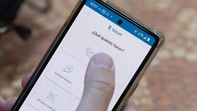 Primer plano de un usuario seleccionando la opción de enviar o solicitar dinero en la pantalla de Bizum.